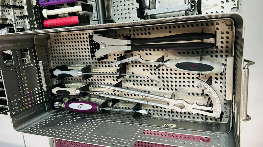 Instrumentos cirúrgicos organizados em case metálico com identificação de itens.